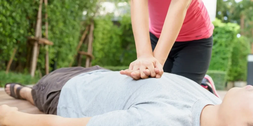 Person performing CPR chest compressions on an adult outdoors